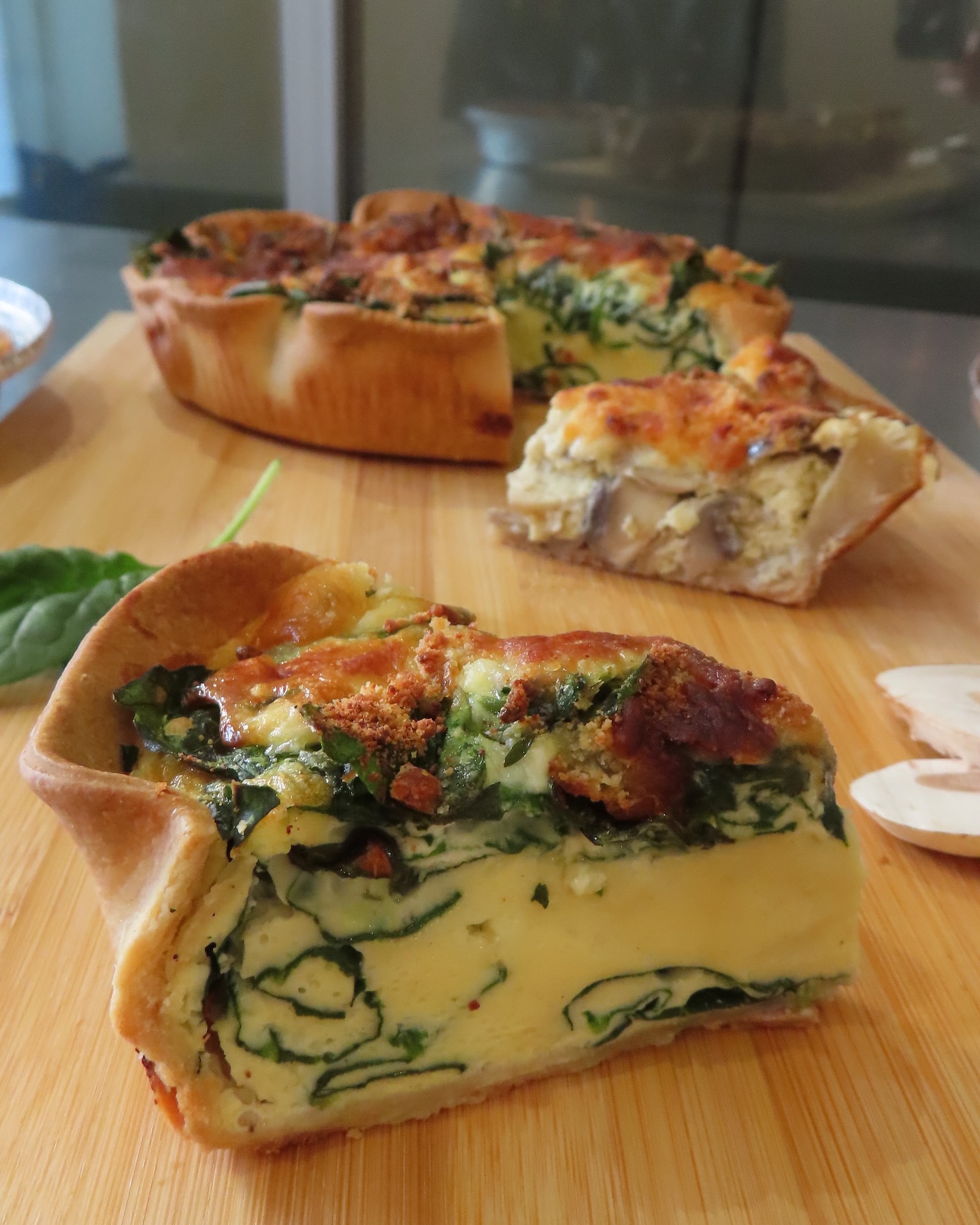 Sliced spinach quiche on wooden cutting board