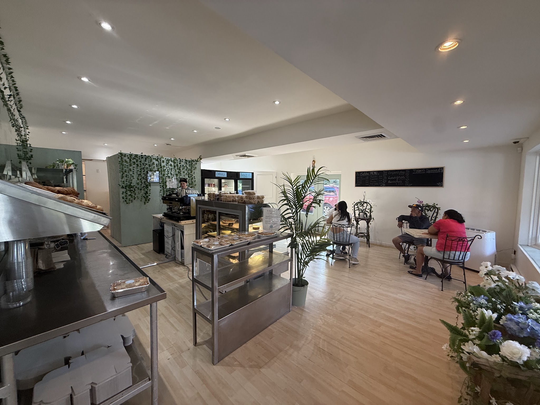 Bright, welcoming interior of Sainte Marie Pâtisserie with pastry display cases, tropical plants, and customers seated at tables