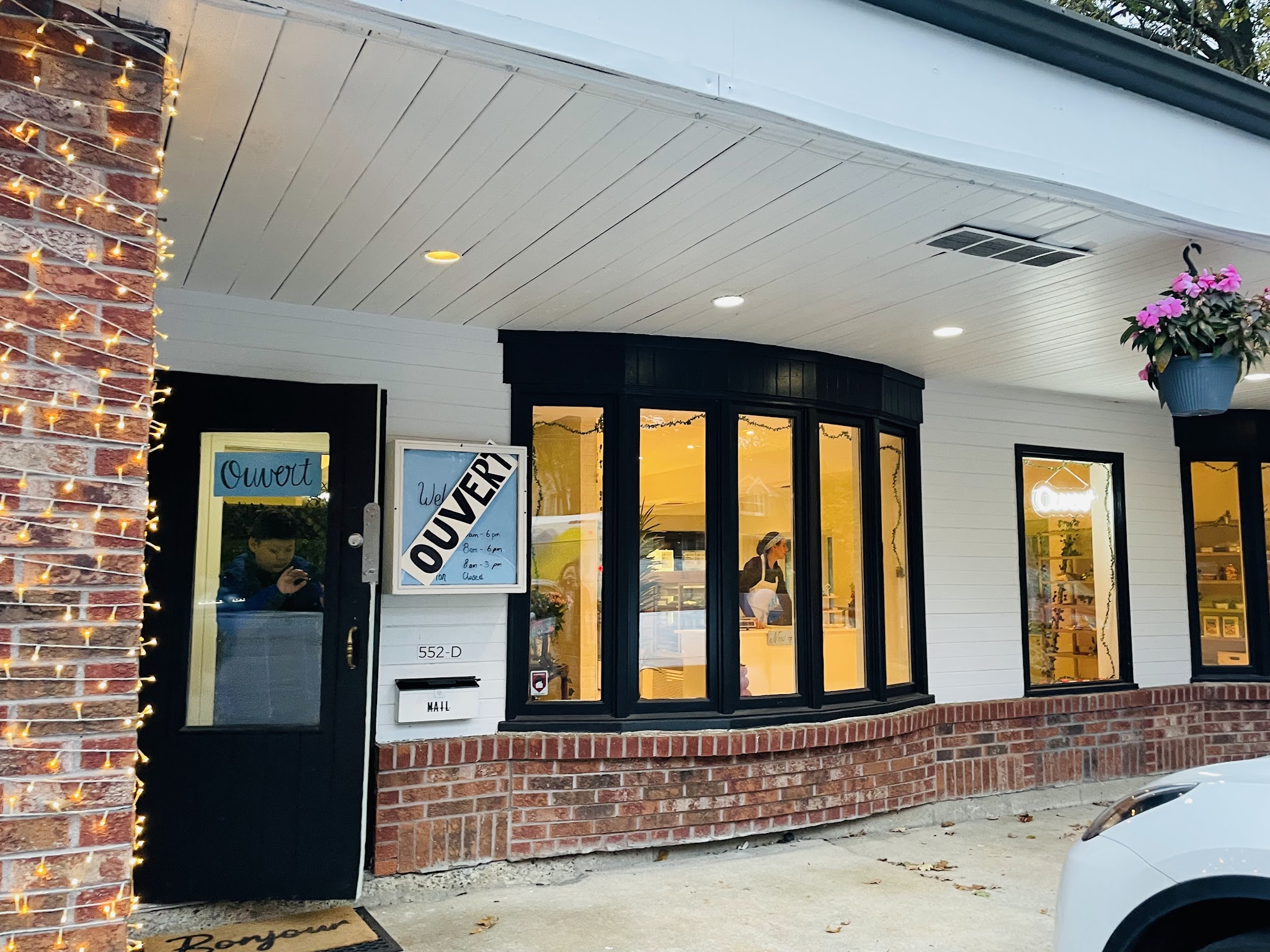 Evening exterior of Sainte Marie Pâtisserie storefront with warm interior lights glowing through the arched windows